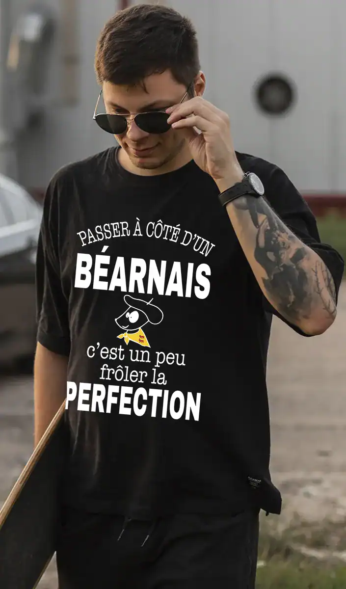 Homme portant un t-shirt noir à message béarnais humoristique « Passer à côté d’un Béarnais c’est un peu frôler la perfection », création locale Pilou Shop 64 à Pau