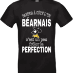 T-shirt noir avec inscription “Passer à côté d’un Béarnais c’est un peu frôler la perfection” et illustration drôle d’un Béarnais avec béret et foulard jaune.