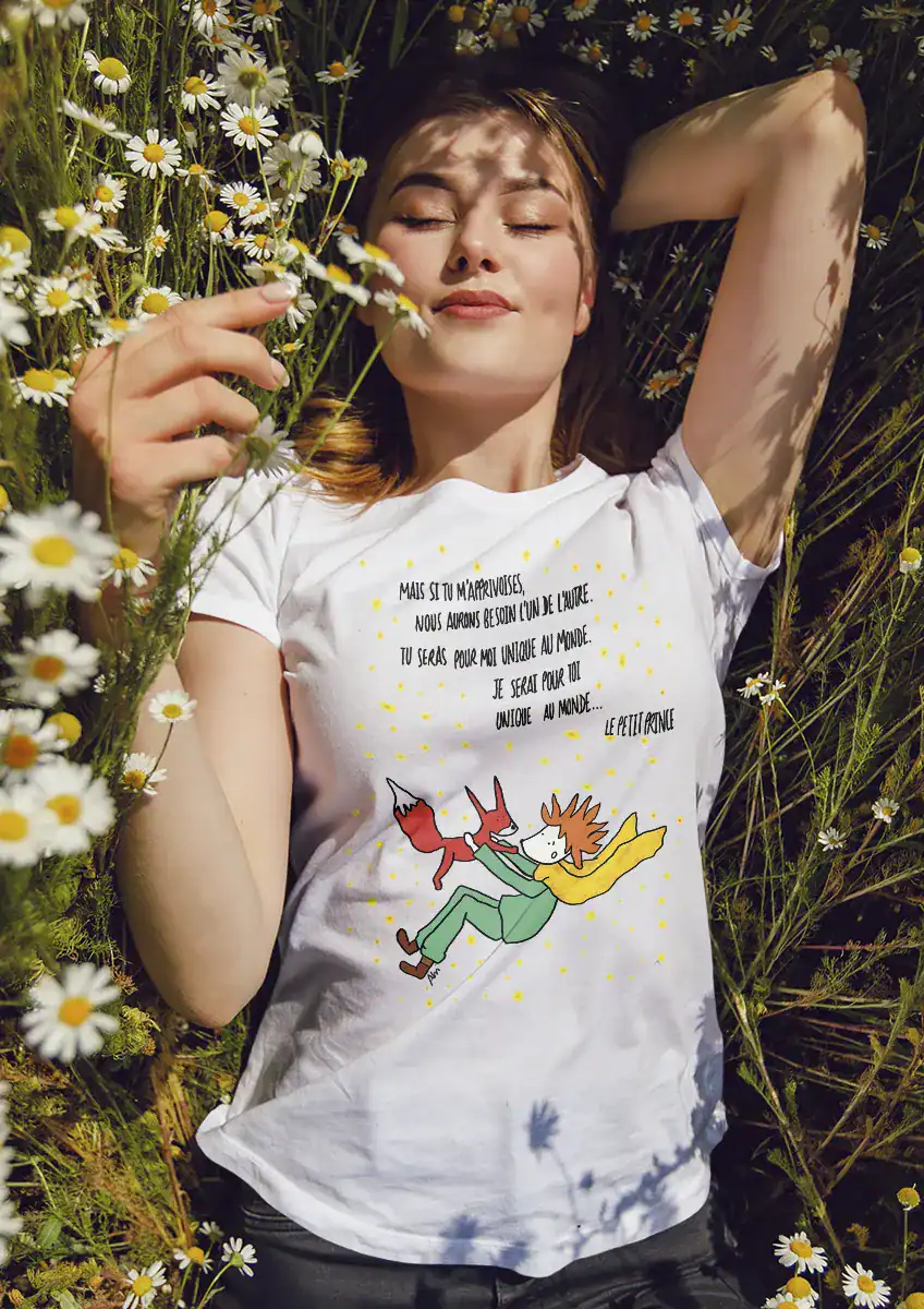 T-shirt femme blanc illustration Le Petit Prince et le renard avec citation poétique allongée dans un champ de marguerites vêtement littéraire artistique doux et intemporel
