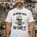 Homme en cuisine de restaurant portant un t-shirt blanc humour “On répond juste oui chef” avec tête de mort chef imprimée