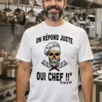 Homme en cuisine de restaurant portant un t-shirt blanc humour “On répond juste oui chef” avec tête de mort chef imprimée