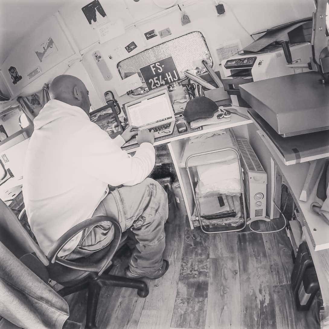 Photo historique des débuts de Pilou Shop 64 montrant Jérôme Lablanche travaillant seul dans sa caravane transformée en atelier de marquage textile avant l’ouverture de l’atelier de Pau.