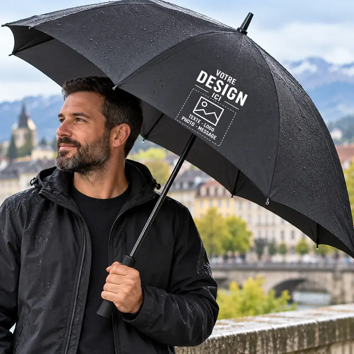 Parapluie noir personnalisable avec logo, photo ou texte, tenu par un homme en extérieur sous la pluie.