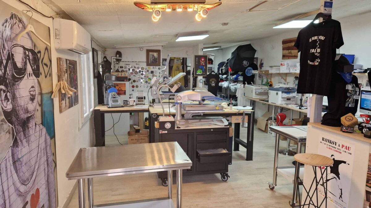 Vue de l’atelier Pilou Shop 64 à Pau, équipé de presses, tables de travail et imprimantes DTF professionnelles pour la personnalisation textile de haute qualité.