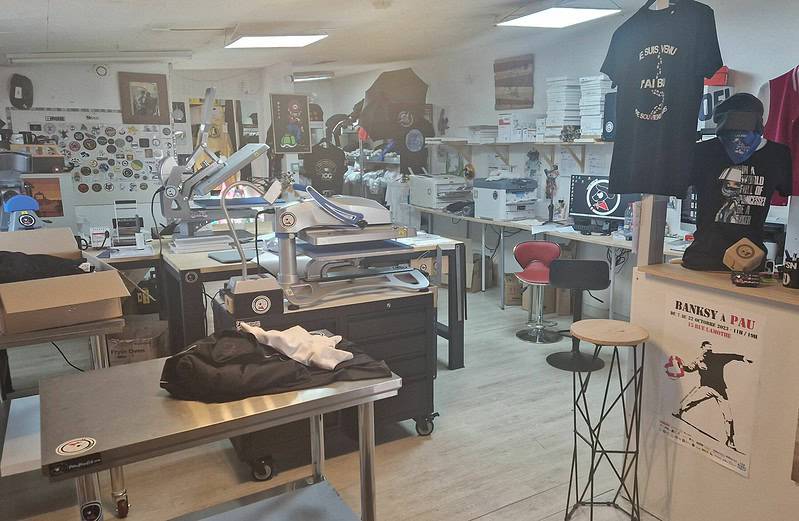 Atelier de sérigraphie avec équipements et vêtements suspendus.