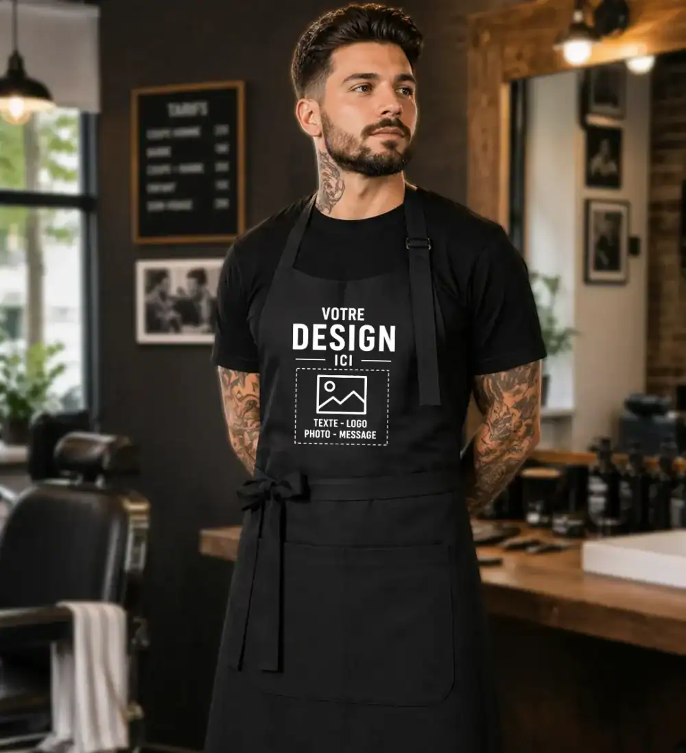 Barbier portant un tablier noir personnalisé avec logo texte ou photo dans un salon professionnel premium