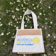 Sac sur herbe avec pâquerettes et logo AcoBeco