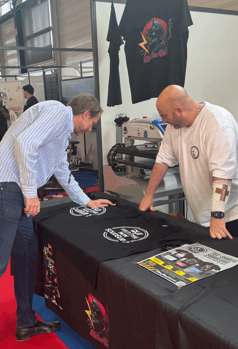 Deux personnes discutent au stand de t-shirts imprimés.