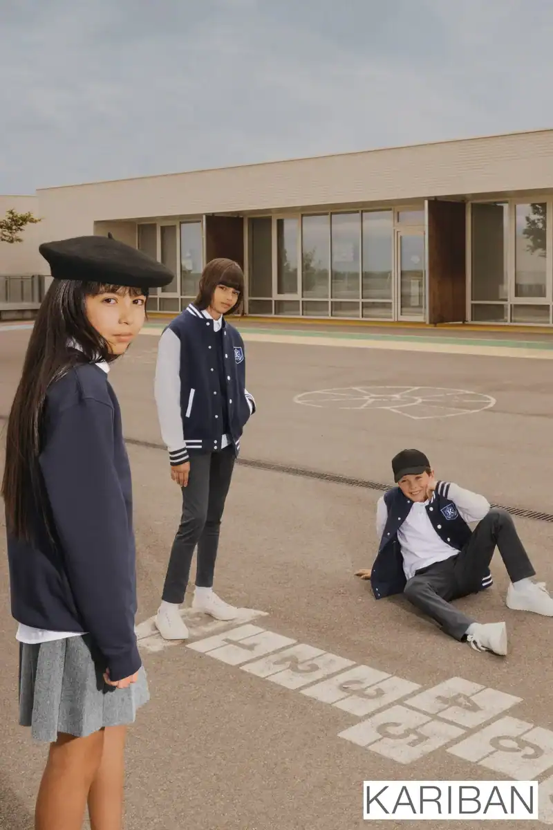 Enfants portant vêtements scolaires Kariban dans une cour.