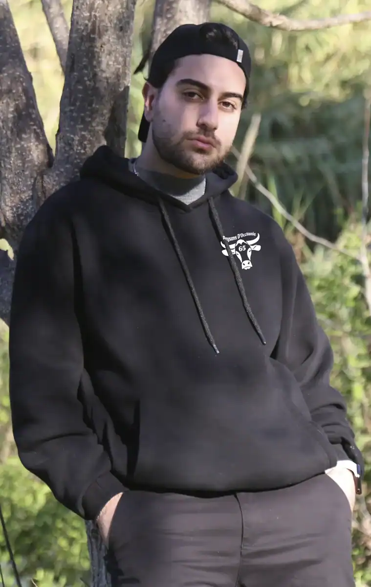 Homme portant sweat noir Paysans d’Occitanie 65 logo blanc poitrine extérieur campagne