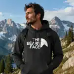 Sweat à capuche noir homme The Béarn Face porté en extérieur montagne avec paysage alpin et sac à dos Pilou Shop 64