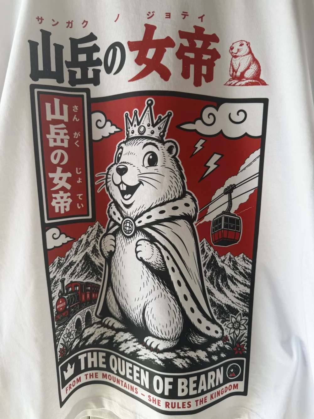 Gros plan du design original Queen of Béarn avec marmotte reine, montagnes, téléphérique et petit train d’Artouste imprimé sur un t-shirt blanc personnalisé à Pau.