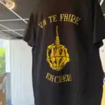 Gros plan du dos du t-shirt Les Mains d’Or avec le design Va te faire encrer suspendu dans l’atelier Pilou Shop 64