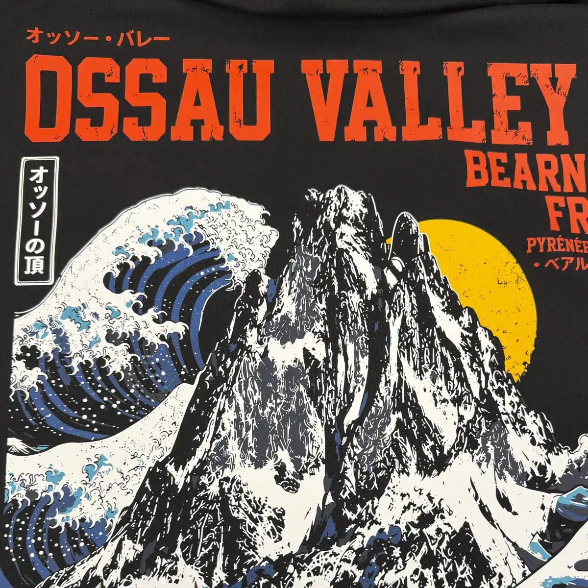 Détail du marquage DTF Ossau Valley sur sweat noir, avec le Pic du Midi d’Ossau et des vagues japonaises.